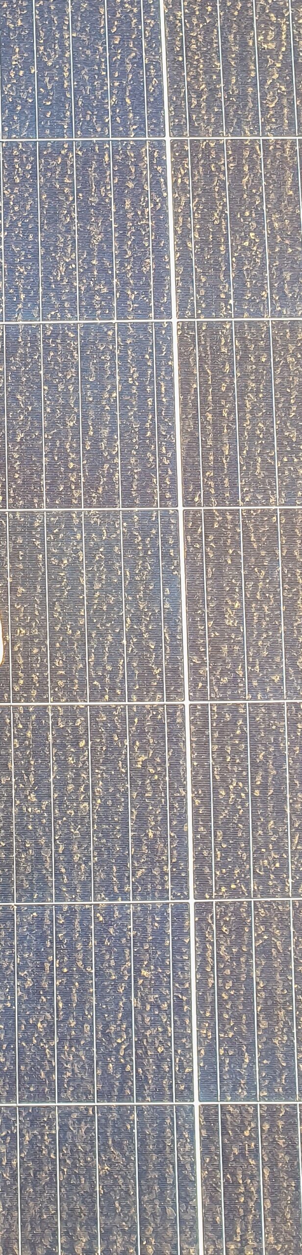 A top view of a squeegee on a dirty solar panel under the sunlight